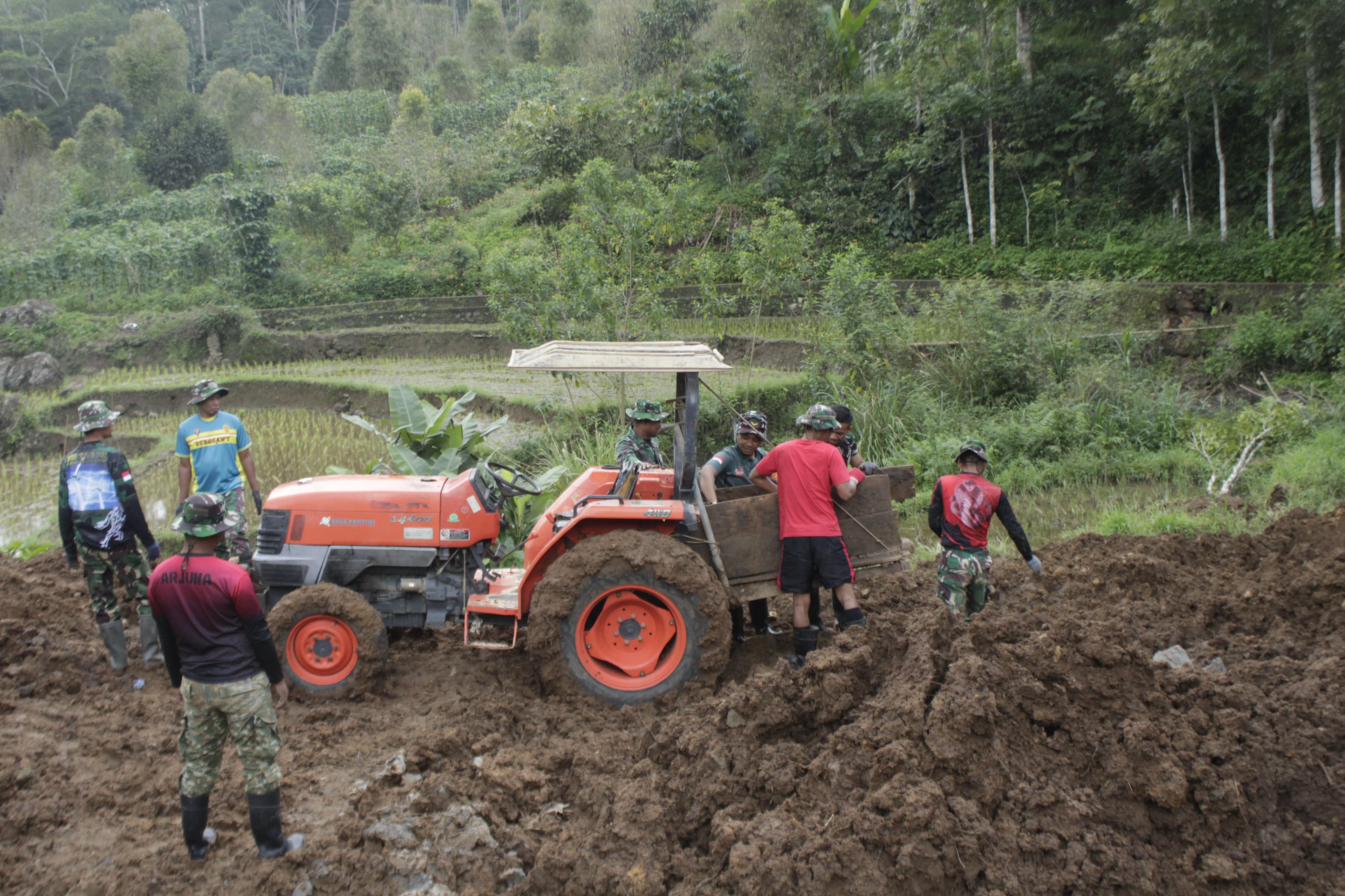 Feature Oleh      : Letkol Arm Dian Akhmad Arifandi, S.E., M.Han.                 (Dansatgas TMMD Reh Ke 121 Kodim 1424/Sinjai)  Kabut putih tebal menyelimuti setiap pagi Desa Arabika, sebuah desa kecil yang terletak di lereng Gunung Bawakaraeng, Kecamatan Sinjai Barat, Kabupaten Sinjai. Desa ini berada di ketinggian 2.840 meter di atas permukaan laut, membuatnya seolah-olah berada di atas awan. Suasana pagi di desa ini selalu tenang, seolah waktu berjalan lebih lambat di sini. Namun, ketenangan itu terganggu oleh raungan keras dari sebuah dump truck yang berjuang untuk bergerak maju di tengah lumpur. Hujan deras yang turun semalam membuat jalan tanah di desa ini berubah menjadi jebakan lumpur yang lengket. Ban kendaraan besar itu hampir separuh tenggelam, terjebak dalam kubangan lumpur yang mengancam kelancaran misi. Dump truck tersebut membawa material batu untuk pembangunan di lokasi kegiatan TMMD (TNI Manunggal Membangun Desa), sebuah inisiatif besar dari Kodim 1424/Sinjai. Kegiatan ini bertujuan membangun jembatan, lapis tebing, dan saluran gandeng—sarana vital bagi warga desa yang akan mendukung kesejahteraan dan mobilitas mereka. Di lokasi, sejumlah anggota Satgas TMMD Kodim 1424/Sinjai segera bereaksi, mencoba mendorong dump truck tersebut dengan sekuat tenaga. Namun, semua upaya tampak sia-sia. Lumpur yang licin membuat roda hanya berputar tanpa pergerakan berarti. Keringat mulai bercucuran, tetapi semangat tak pernah surut. Tim tahu, setiap detik yang terbuang akan memperlambat jalannya pembangunan yang sangat dibutuhkan warga desa. Situasi ini membuat kami berpikir keras. Jika masalah ini tidak segera teratasi, suplai material akan terhambat, mengganggu kelancaran pembangunan jembatan, lapis tebing, dan saluran gandeng—sasaran utama TMMD Reguler ke-121 Tahun 2024 kali ini.